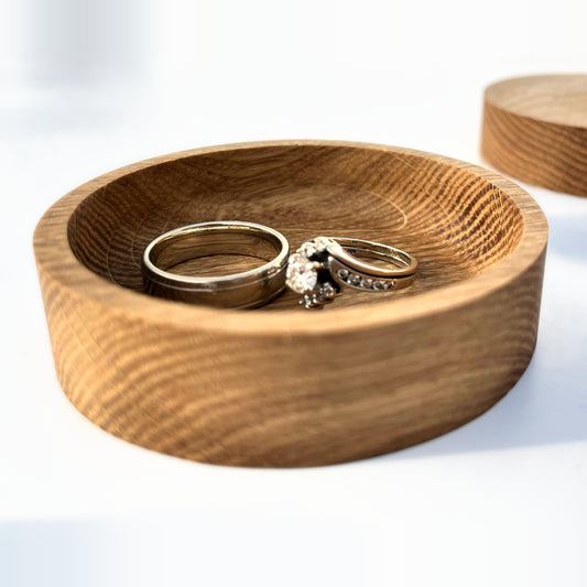 Solid oak 3 inch round ring tray holding a wedding band and engagement ring, front view