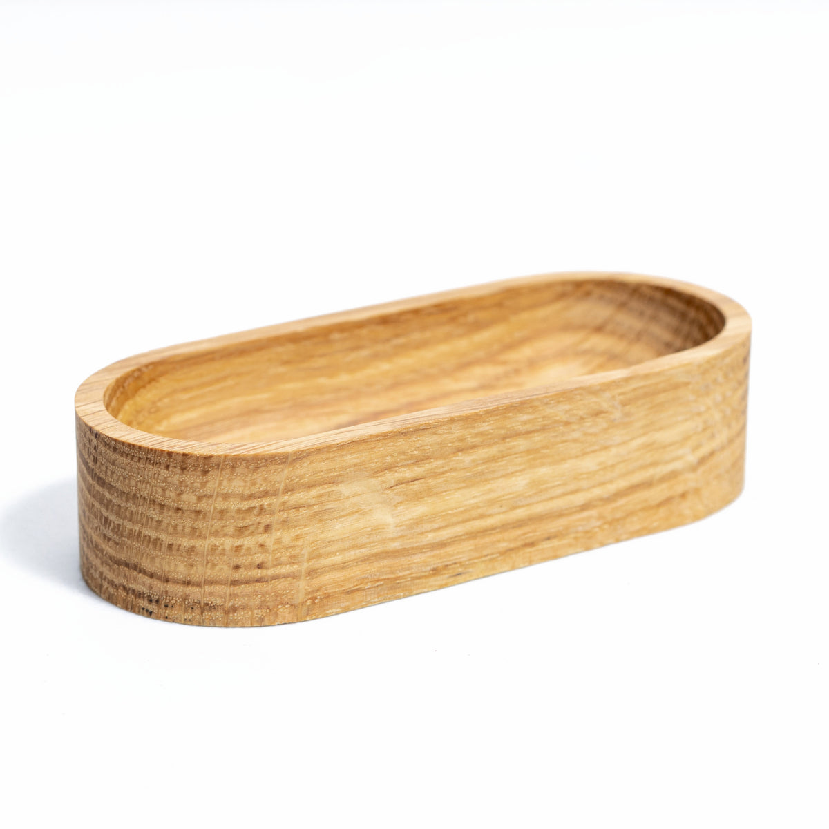 Solid oak 4 x 2 inch oval jewelry dish, angled side view showing the oak grain